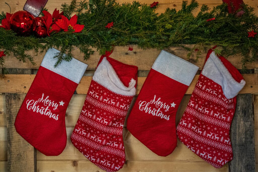 Vibrant red Christmas stockings hanging on a wooden wall with festive decorations.