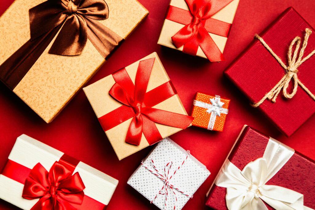 Top view of beautifully wrapped scuba diving Christmas gifts with red and brown ribbons on a vibrant red background.